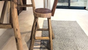 Une pièce avec une table en bois, une chaise, une plante en pot et une vue sur des palmiers à travers une porte vitrée.