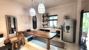 Une cuisine moderne dotée d’un grand îlot central, de luminaires suspendus et d’un réfrigérateur.