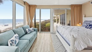 Un dormitorio con un ventanal grande, una cama, un sofá y un ventilador de techo.