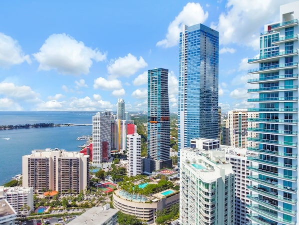 A high-rise hotel with multiple floors, a swimming pool, and a view of the sea.