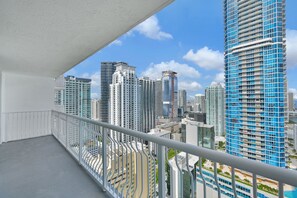 A balcony with a view of high-rise buildings, including a blue glass tower.