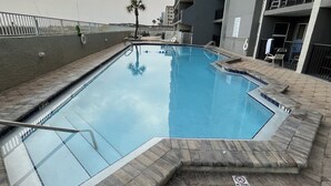 Una piscina con bordo piastrellato, circondata da un edificio con balconi e ringhiera.