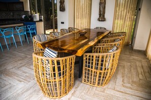 A dining area with a large wooden table surrounded by wicker chairs with striped cushions. - Casa privada en la Isla Barú (Cartagena)