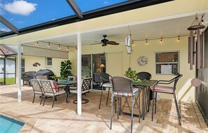 An outdoor patio with a covered seating area, a pool, and a barbecue grill.