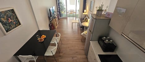 A narrow kitchen with a dining area, a refrigerator, and a microwave.