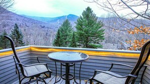 An outdoor deck with a table and chairs, overlooking a mountainous landscape. - Loon Outlook - Best View, <3min to Loon (Lincoln)