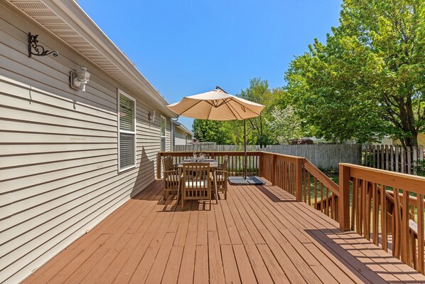 A wooden deck with a table and chairs, a beige umbrella, and a wooden railing. - Large family-friendly home w/ pool table, close to Muskegon Lake & Lake Michigan (Muskegon)