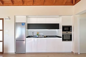 A modern kitchen with white cabinetry, stainless steel appliances, and a wooden ceiling.