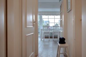 Un couloir menant à un balcon agrémenté de balustrades et de chaises blanches.