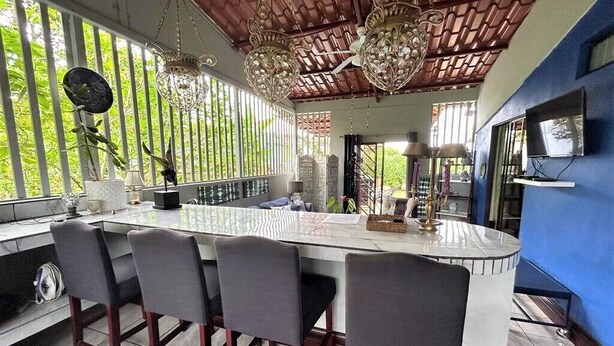 A modern kitchen with a large island, bar stools, and a TV mounted on the wall. - Casa Sophia (Guapiles)