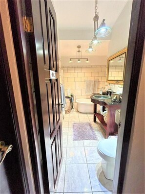 A bathroom with a toilet, sink, and bathtub, featuring a tiled floor and a hanging light fixture. - Casa Sophia (Guapiles)