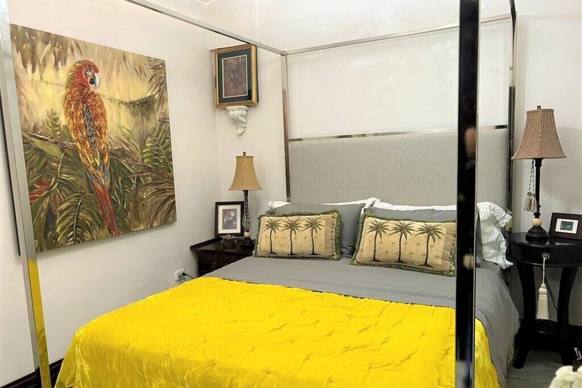 A bedroom with a bed, a nightstand, a lamp, a painting, and a framed picture on the wall.