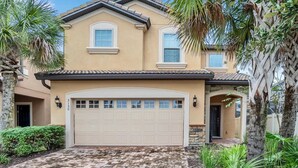A two-story house with a beige facade, a large garage, and a brick driveway. - Paradise 6 BR home - private pool and spa near all Disney parks - Free pool heat (Kissimmee)