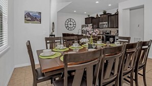 A dining area with a round table set for six, surrounded by dark wooden chairs. - Paradise 6 BR home - private pool and spa near all Disney parks - Free pool heat (Kissimmee)
