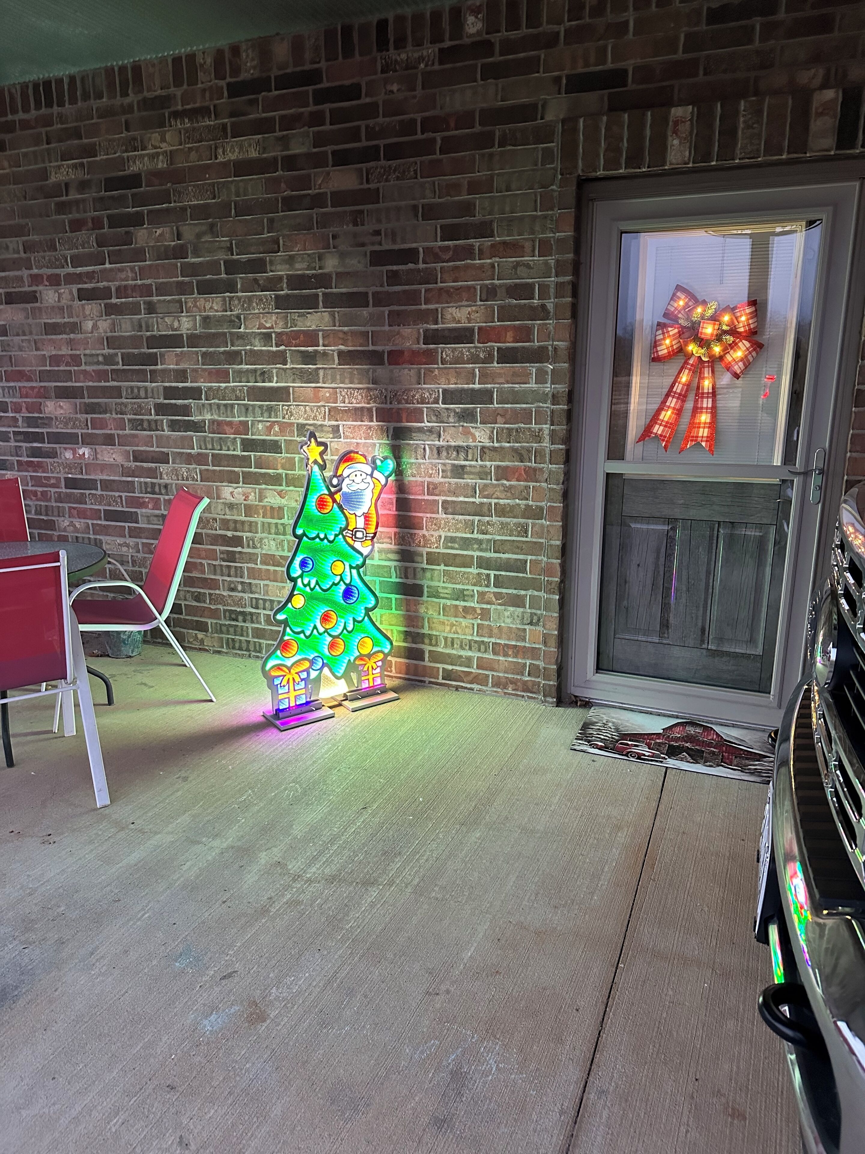 Un mur de briques décoré d’un sapin de Noël et une porte ornée d’un nœud.