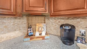 A kitchen with wooden cabinets, a coffee maker, and a tray with cups and a coffee mug.