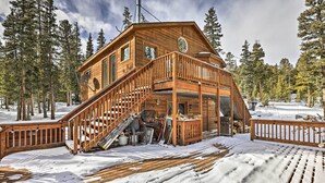 Eine Holzhütte mit einer Holzterrasse und einer Treppe, die zu einem Balkon führt.