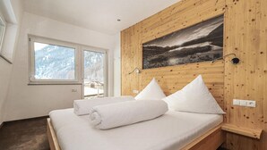 Een slaapkamer met een houten hoofdbord, een groot raam en een schilderij van een landschap.