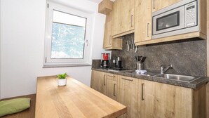 Een kleine keuken met houten kastjes, een magnetron, een koffiezetapparaat en een spoelbak.