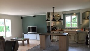 A modern kitchen with a central island, built-in appliances, and a dining area with a table and chairs.