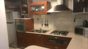 Una cocina compacta con estufa a gas, pileta doble, horno y alacenas de madera.