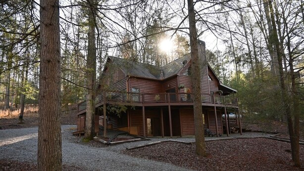 A cabin with a balcony, surrounded by trees.