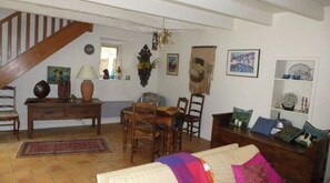 Een gezellige woonkamer met een houten trap, een eethoek en een boekenkast.
