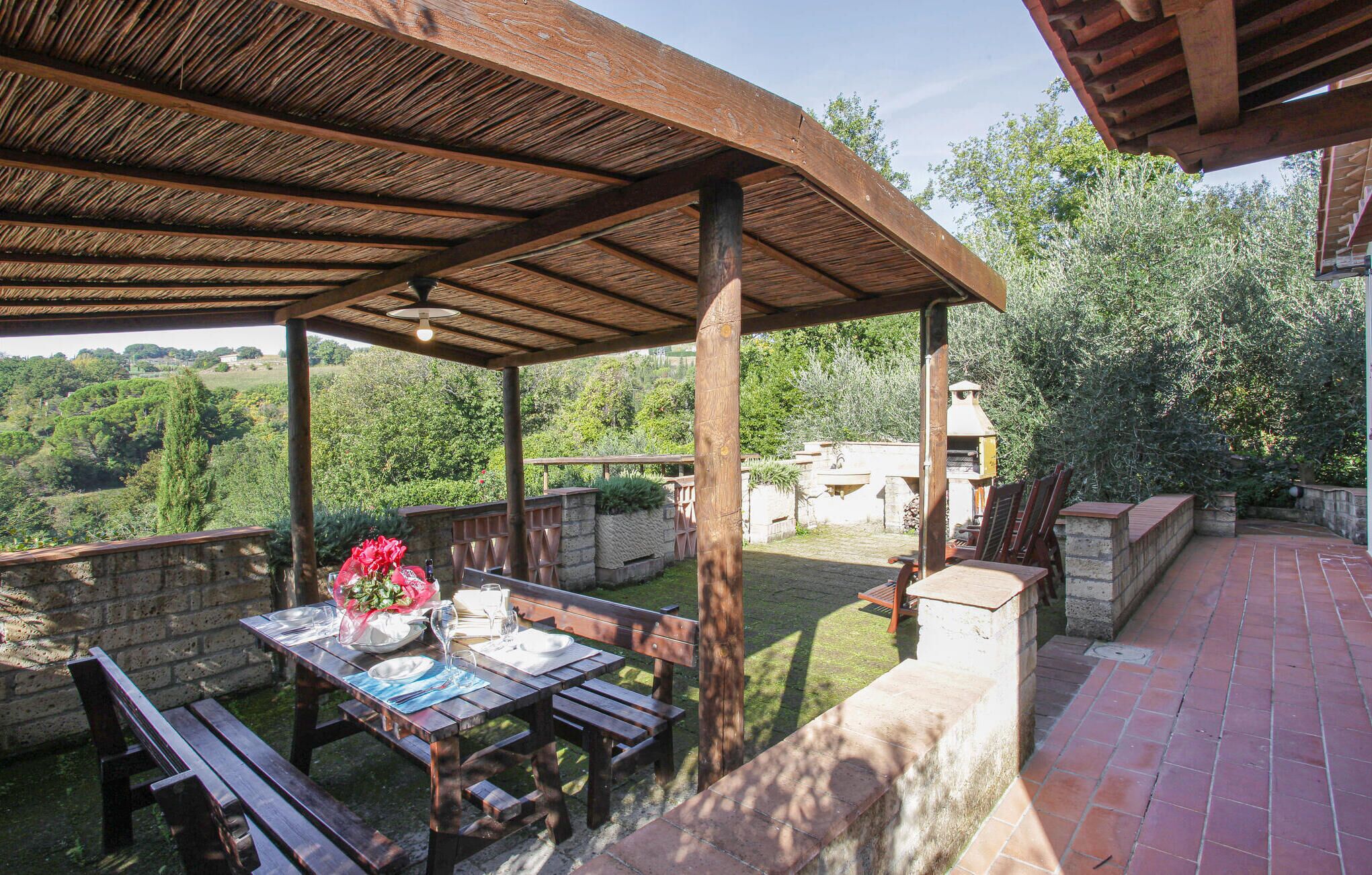 Eine Terrasses mit Holz-Pergola, Steinmauern und einem Backsteinboden.