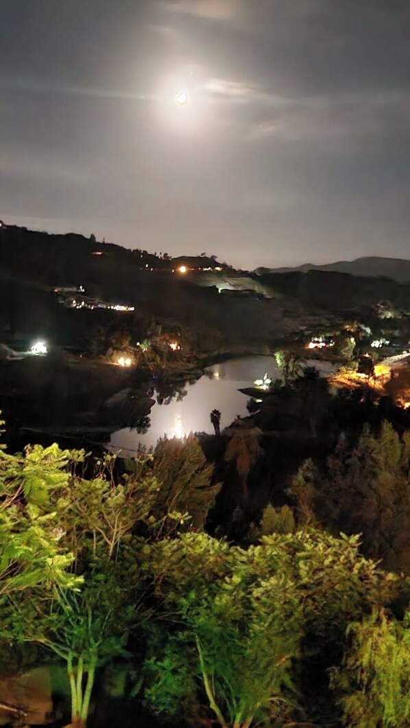 A nighttime view of a river valley with illuminated buildings and a prominent moon in the sky. - The most breathtaking lake and mountain view (Fallbrook)