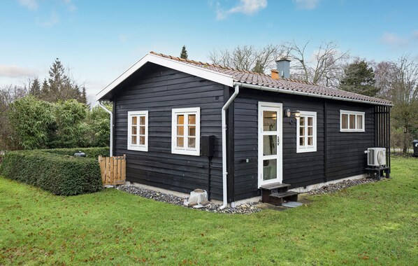 Una casa de madera negra con detalles blancos, un techo de tejas y un pequeño porche.