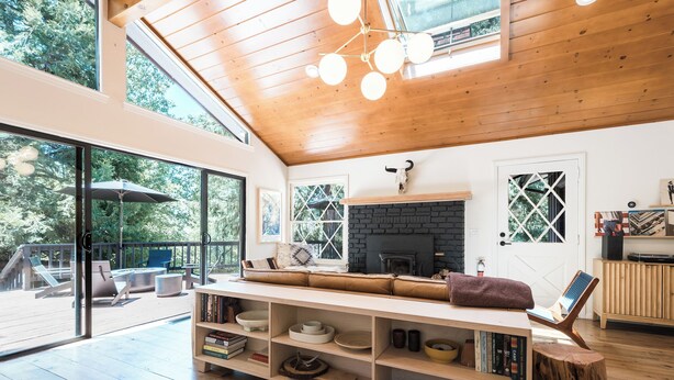 A spacious living area with a wooden ceiling, a fireplace, and a large window overlooking a deck. - Mountain mod cabin w/ EV charging - Fernwood (Idyllwild-Pine Cove)