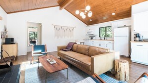 A modern living room with a leather sofa, wooden coffee table, and a dining area. - Mountain mod cabin w/ EV charging - Fernwood (Idyllwild-Pine Cove)