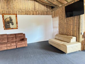 Relax in a cozy space with a large projection screen, tufted sofas, and a flat-screen TV.