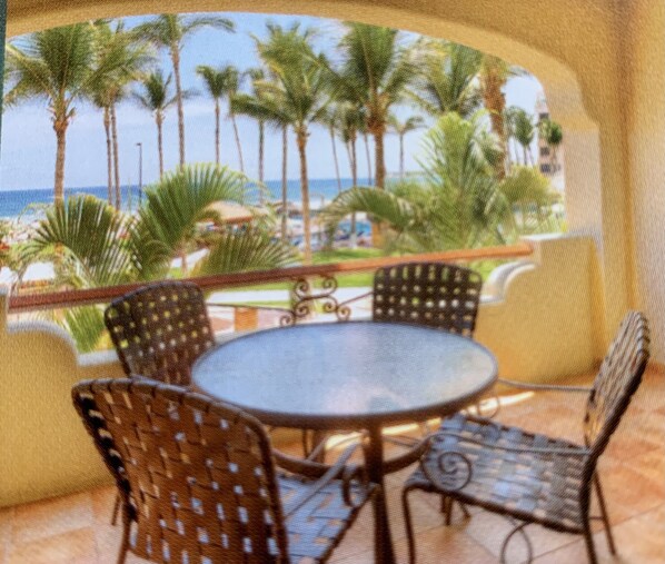 A round table with four chairs, a view of palm trees, and a distant body of water. - Magnificent View of Pacific, Pool, Mama Mia Restaurant while Relaxing in the SUN (San José del Cabo)