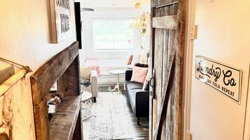 A narrow hallway with a wooden bench, a rug, and a door with a sign.
