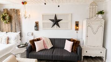 A cozy living room with a dark grey sofa, a white cabinet, and a star wall decoration.