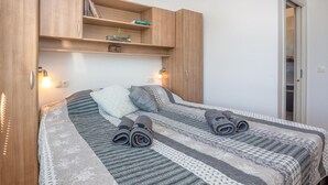Et soveværelse med en seng, to puder, et natbord, en reol med bøger og en dør.