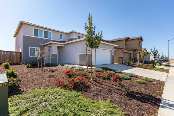 A modern two-story house with a garage, surrounded by landscaped gardens and a clear sky. - Private Rancho Cordova Retreat (Rancho Cordova)