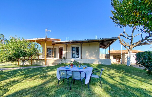 A house with a patio table set for two, a covered outdoor seating area, and a well-maintained lawn. - 3 bedroom lovely home in Lakkopetra (Lakkopetra)