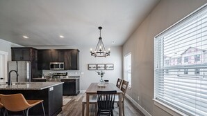 Una cocina moderna con armarios de madera oscura, una isla central y una zona de comedor con una araña.