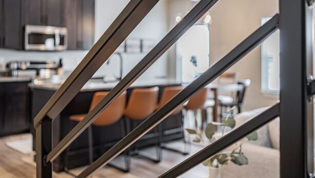 Una cocina moderna con armarios oscuros, microondas y un comedor con sillas y mesa.