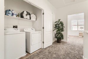 Convenient laundry facilities with a washing machine and dryer, plus storage for cleaning supplies.