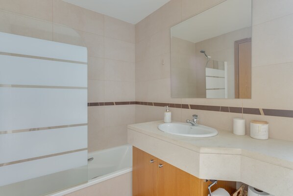 Un baño moderno con bañera, lavamanos y espejo.