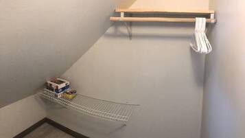 A corner laundry area with a drying rack and a shelf with folded clothes.