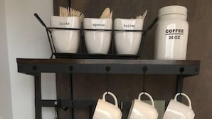 Een kitchenette met een koffiezetapparaat, een waterkoker en een koffiebus op een plank.