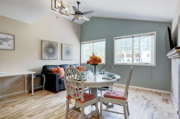 A dining area with a round table, chairs, and a ceiling fan. - Summit Place 4B | Great Value for a Family of 4 (Canmore)