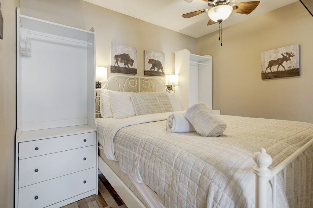 A bedroom with a bed, a wardrobe, and a ceiling fan.