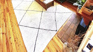 Un salon comprenant un canapé, des fauteuils, une table basse et une grande fenêtre avec des stores.