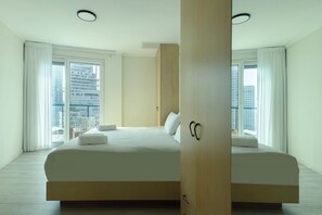 Una habitación de hotel moderna con una cama grande, vista a la ciudad y una puerta corredera.