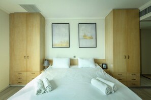 Habitación de hotel con una cama grande, un armario de madera y dos cuadros en la pared.